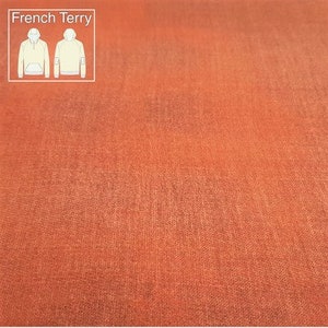 Könnte beinhalten: Nahaufnahme eines rostfarbenen French-Terry-Stoffes. Der Stoff hat eine weiche, strukturierte Oberfläche.