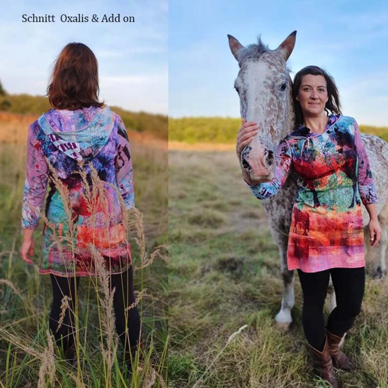 May include: A woman wearing a colourful hooded dress with abstract patterns stands in a field with a horse. The dress has a long sleeve and a loose fit. The woman is holding the horse's head with her left hand. The horse is white with brown spots. The background is a field of green grass.