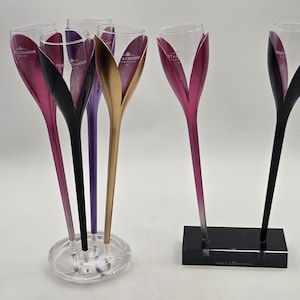 May include: A white ceramic mug with a black handle and the text "But First, Coffee" in a black, handwritten-style font. The mug is on a white surface.