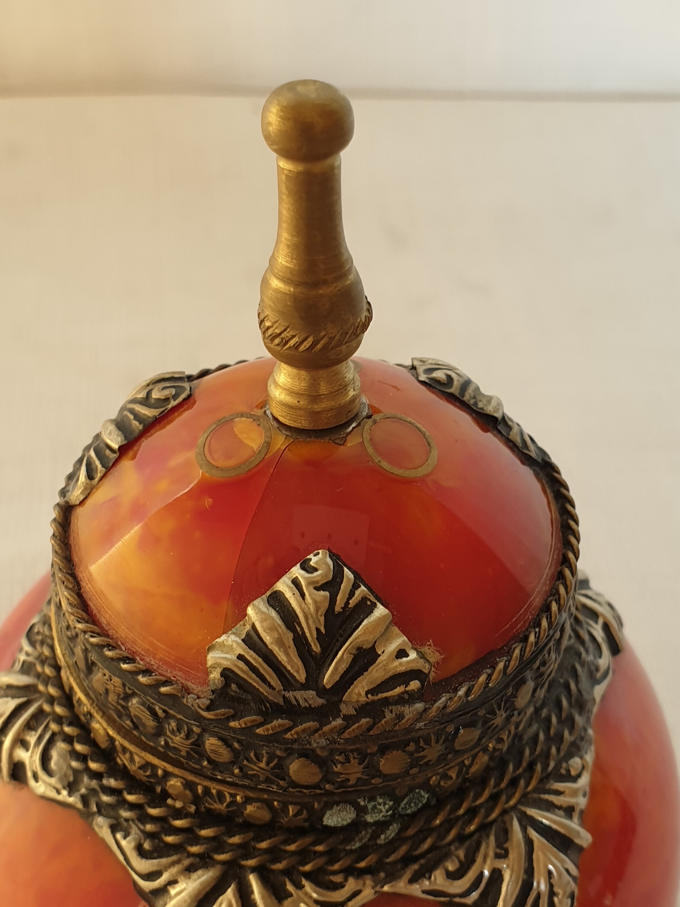 Two ornate orange lid jars, finished with brass ornaments.