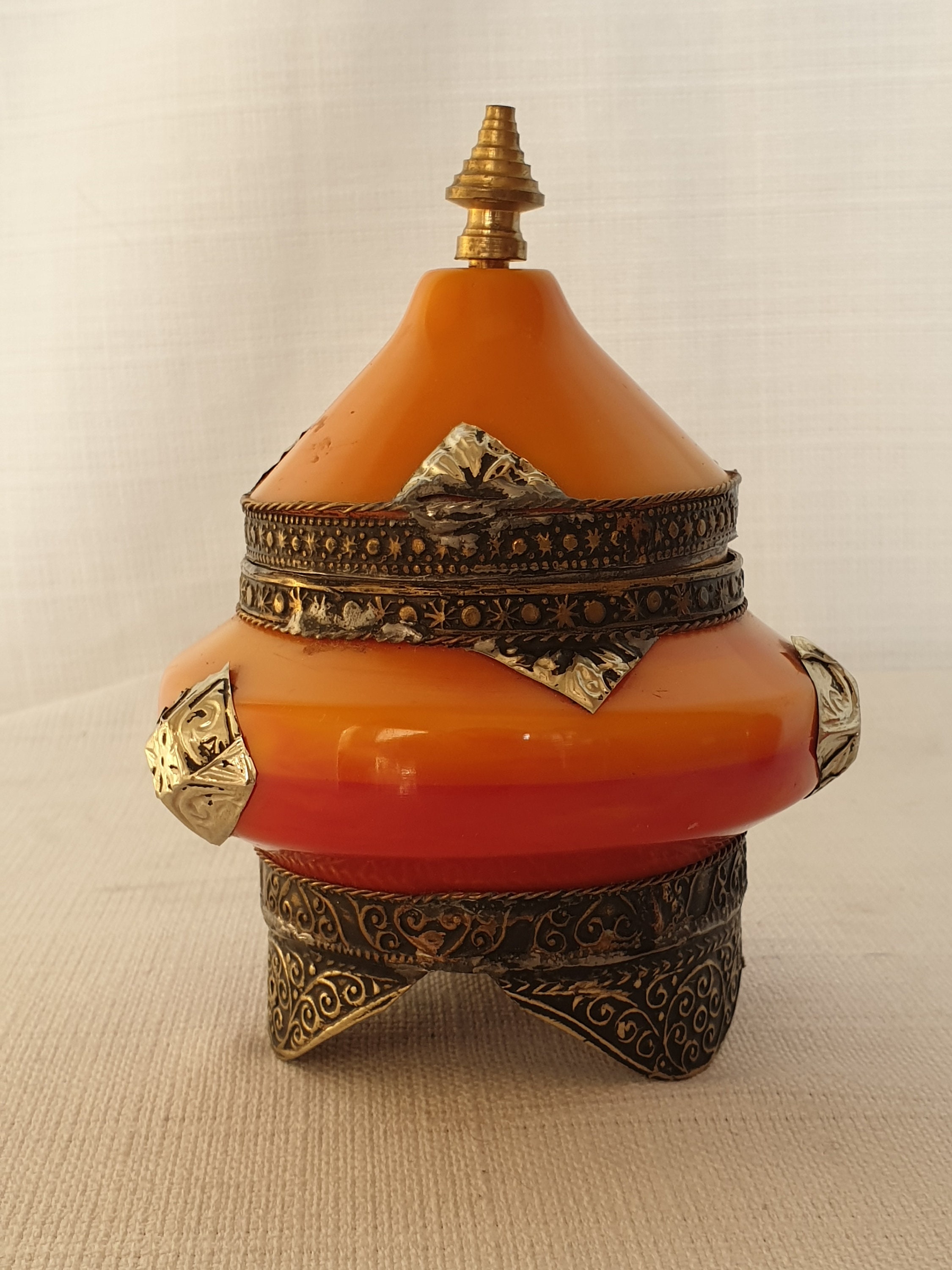 Two ornate orange lid jars, finished with brass ornaments.