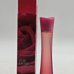 May include: A pink perfume bottle and its matching box. The bottle is a slender, curved shape with a pink cap. The box is tall and rectangular, with a rose graphic and the text "PUR DESIR de ROSE". The bottle contains 60 ml of perfume.