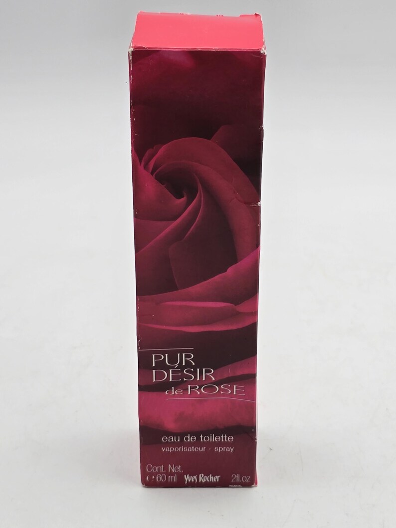 May include: A dark red rectangular box of "Pur D&eacute;sir de Rose" eau de toilette. The box features a rose image. The text "PUR D&Eacute;SIR de ROSE" is printed in white. The box contains 60 ml of eau de toilette.