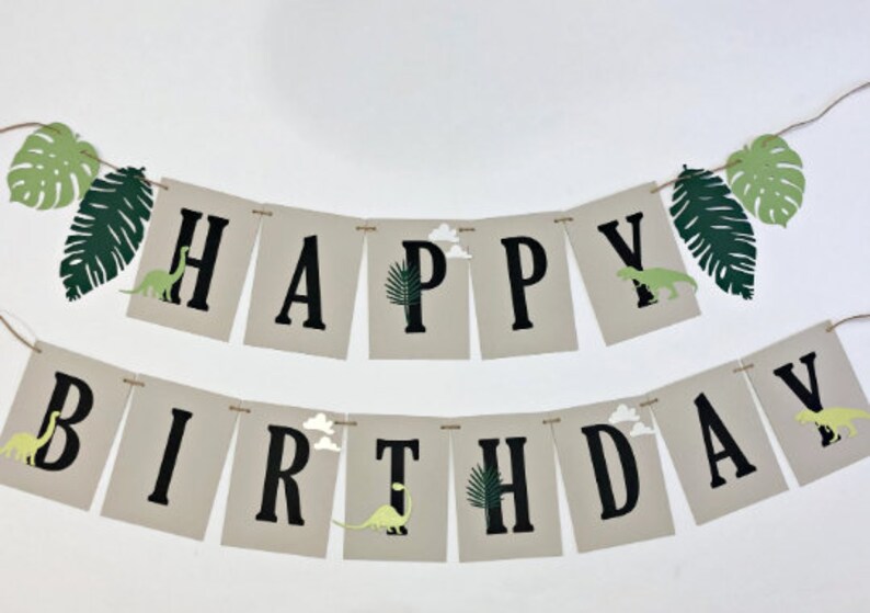 K&ouml;nnte beinhalten: Ein Banner mit den Worten "Happy Birthday" in schwarzen Buchstaben auf beigefarbenem Hintergrund. Das Banner ist mit gr&uuml;nen Bl&auml;ttern und Dinosauriern verziert.