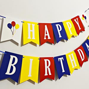 May include: Two colorful birthday banners. The top banner spells "HAPPY" in white letters on yellow, red, and blue pennants. The bottom banner spells "BIRTHDAY" in white letters on blue, yellow, and red pennants. Each banner has a balloon graphic.