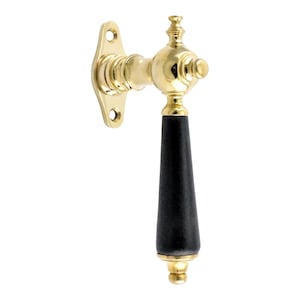 May include: A gold window handle with a black wooden knob. The handle has a decorative design and is attached to a wall plate.