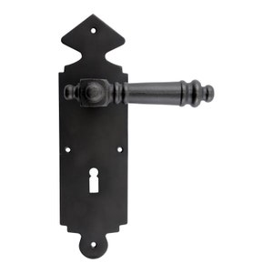 Peut inclure: Poignée de porte en fonte noire avec un trou de serrure et un design décoratif. La poignée a une forme carrée avec une extrémité arrondie.