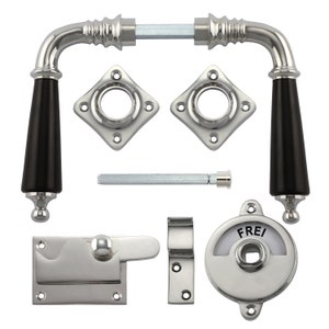 Könnte beinhalten: Ein Satz polierter Nickel-Türbeschläge mit schwarzen Griffen, bestehend aus einem Riegel, einer Schließplatte, einem Türknauf und zwei Rosetten. Der Türknauf hat eine runde, silberne Platte mit dem Wort "FREI" darauf.