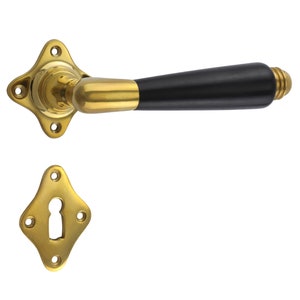 Puede incluir: Una manilla de puerta dorada con un pomo de madera negro. La manilla tiene un diseño decorativo y una cerradura.