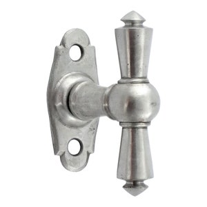 May include: A silver-toned metal window latch with a decorative, pointed handle. The latch has a rectangular base with two holes for mounting.