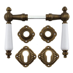 Puede incluir: Un juego de herrajes para puertas de estilo antiguo en acabado latón con manijas de porcelana blanca. El juego incluye dos pomos de puerta, dos rosetas y una manija de palanca.