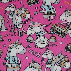 Könnte beinhalten: Rosafarbener Stoff mit einem sich wiederholenden Muster aus weißen Einhörnern, die Musikinstrumente spielen. Die Einhörner tragen bunte Kleidung und haben Regenbogenmähne und -schwänze. Der Text "STAR" und "rock" ist auf dem Stoff gedruckt.