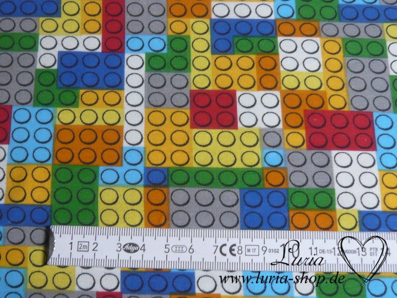 Puede incluir: Una tela colorida con un patr&oacute;n repetitivo de cuadrados de diferentes colores. Cada cuadrado est&aacute; lleno de un patr&oacute;n de peque&ntilde;os c&iacute;rculos. La tela se mide con una regla en cent&iacute;metros.