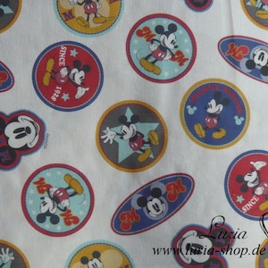 Könnte beinhalten: Weißer Stoff mit einem sich wiederholenden Muster aus bunten Mickey Mouse-Designs. Die Designs zeigen Mickey Mouse in verschiedenen Posen, darunter winkend, einen Stern haltend und einen Hut tragend. Der Text "Since 1928" und "Mickey Mouse" ist ebenfalls in den Designs enthalten.