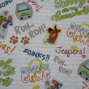 May include: A white fabric with a repeating pattern of Scooby Doo characters and phrases. The phrases include "Scooby ate my homework", "Mystery Gang", "Jinkies", "Zoinks", "Jeepers", and "Ruh-Roh".