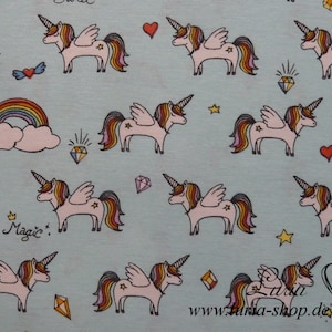 以下が含まれることがあります： 薄い青色の生地に、ユニコーン、虹、星、ハート、ダイヤモンドが繰り返し描かれたパターンがあります。ユニコーンはピンクで、虹色のたてがみと尻尾があり、翼も付いています。パターンには「Magic.」という文字も含まれています。
