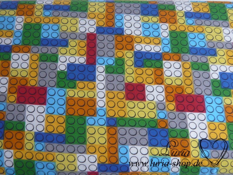 Puede incluir: Una tela colorida con un patr&oacute;n repetitivo de cuadrados de diferentes colores. Cada cuadrado est&aacute; lleno de peque&ntilde;os c&iacute;rculos en blanco, amarillo, naranja, rojo, azul, verde y gris. La tela tiene un fondo blanco.