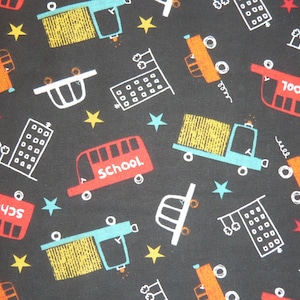 Könnte beinhalten: Ein schwarz-weißes Stoffmuster mit sich wiederholenden Motiven von Schulbussen, Lastwagen, Gebäuden und Sternen. Die Busse zeigen die Aufschrift "School" und "School Bus".