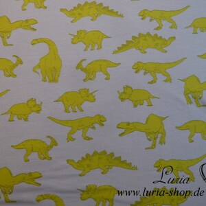 May include: White fabric with a repeating pattern of yellow dinosaurs. The dinosaurs are in various poses and sizes. The fabric has a subtle texture.
