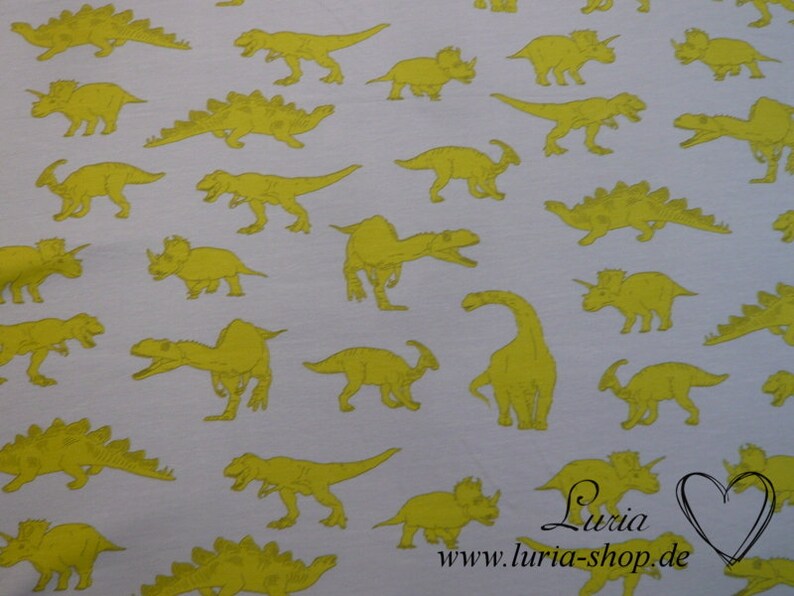May include: White fabric with a repeating pattern of yellow dinosaurs. The dinosaurs are in various poses, including walking, running, and standing. The fabric has a subtle texture.
