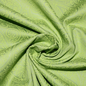 Könnte beinhalten: Grüner Stoff mit Paisley-Muster und weicher, seidenartiger Textur. Der Stoff ist gefaltet und drapiert und zeigt das komplizierte Design.