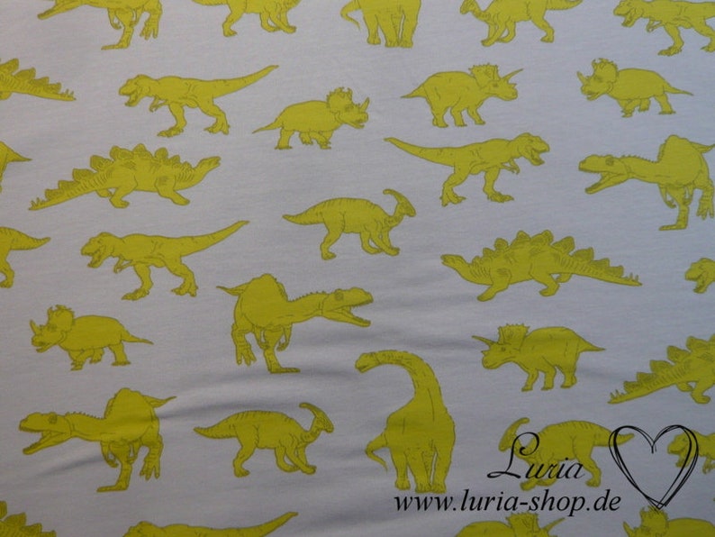 May include: White fabric with a repeating pattern of yellow dinosaurs. The dinosaurs are in various poses, including walking, running, and standing. The fabric is perfect for crafting projects, such as making clothes, bags, and home decor.