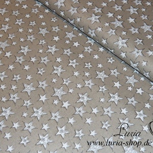 May include: Beige fabric with a white star pattern. The fabric has a subtle sheen and the stars are outlined in a darker shade of white.