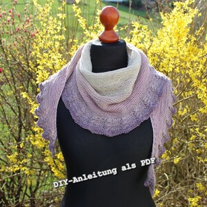 May include: A purple and white knitted shawl with a lacy edge. The shawl is draped over a mannequin against a background of yellow flowers. The text "DIY-Anleitung als PDF" is printed on the bottom of the image.