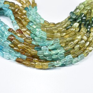 May include: A strand of faceted gemstone beads in shades of green, blue, and yellow. The beads are rectangular in shape and have a smooth, polished finish.