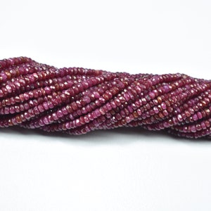 May include: A strand of ruby red faceted gemstone beads. The beads are small and round, and they are strung together on a clear thread.