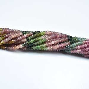 Op de afbeelding: Een streng multi-kleurige edelsteen kralen. De kralen zijn facetgeslepen en hebben een mix van roze, groene en zwarte kleuren.
