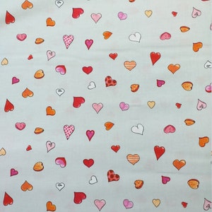 Könnte beinhalten: Ein hellblauer Stoff mit einem sich wiederholenden Muster aus roten, rosa, orangefarbenen und weißen Herzen. Die Herzen sind in verschiedenen Größen und Formen.