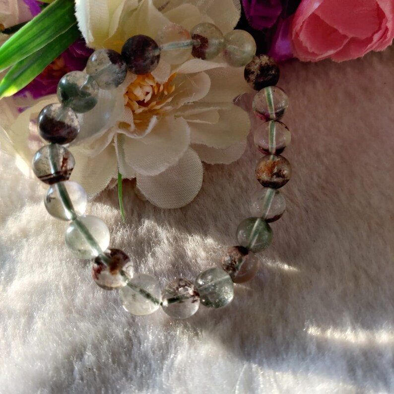 May include: A bracelet made of clear, green, and brown gemstone beads. The beads are round and have a smooth, polished finish.