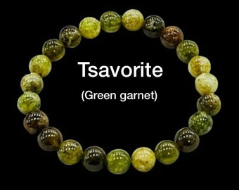 May include: A green gemstone bracelet made of tsavorite, also known as green garnet. The bracelet is made of round beads and has a graduated color scheme, with darker green beads on one side and lighter green beads on the other.