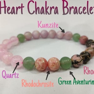 May include: Heart Chakra bracelet featuring pink, green and black beads. The beads are labelled with their corresponding stone names: Rose Quartz, Rhodochrosite, Green Aventurine and Rhodonite.