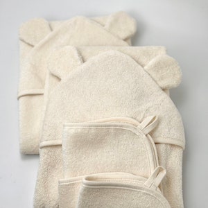 Puede incluir: Tres toallas con capucha y orejas de oso, hechas de un material suave y absorbente. Las toallas est&aacute;n apiladas una encima de la otra, con la toalla superior doblada por la mitad.