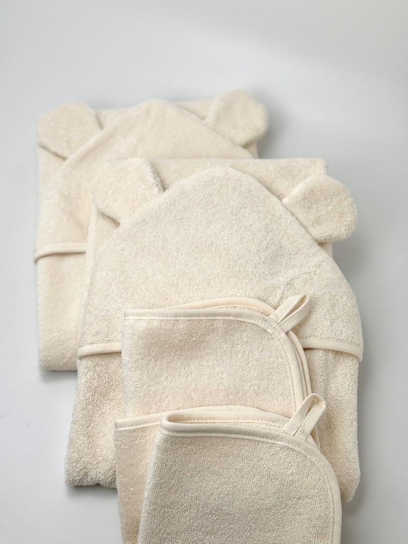 Puede incluir: Tres toallas con capucha y orejas de oso, hechas de un material suave y absorbente. Las toallas est&aacute;n apiladas una encima de la otra, con la toalla superior doblada por la mitad.