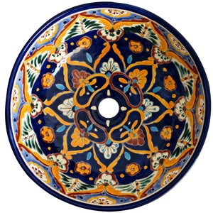 May include: A round, hand-painted ceramic sink basin with a vibrant floral design. The sink features a deep blue background with intricate patterns in yellow, orange, white, and green. A central drain hole is visible.