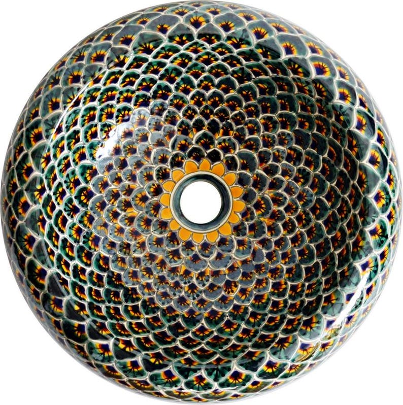 May include: A round, decorative ceramic sink with a detailed pattern. The sink features a repeating design of overlapping, scale-like shapes in shades of green, yellow, and blue. The center has a circular drain surrounded by a yellow floral design.