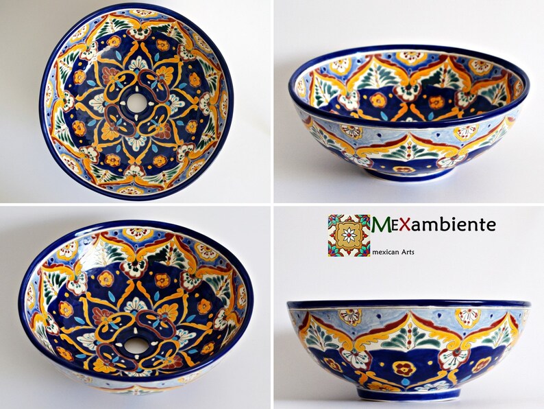 May include: Hand-painted ceramic bowl with a vibrant floral design. The bowl features a deep blue rim and interior, with intricate patterns in yellow, orange, and green. The design includes a central hole, likely for a sink or decorative element.