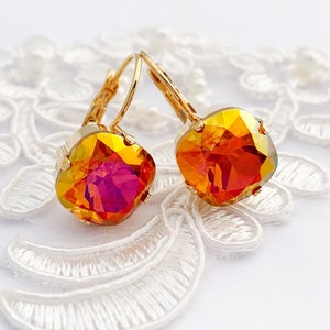 May include: A pair of gold earrings with orange and pink square-shaped crystals.