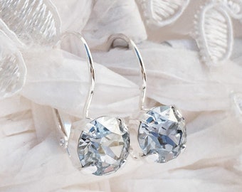 May include: A pair of silver dangle earrings with clear crystal stones.