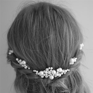 May include: A pearl hair comb with a cluster of pearls in the center and smaller clusters on either side. The comb is designed to be worn in the hair.