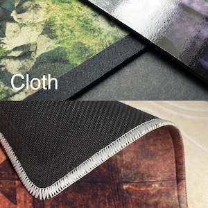 May include: A close-up of a black and white mouse mat with a stitched edge. The mouse mat has a textured surface and is made of cloth. The text "Edge Stitched" is printed on the bottom of the image.