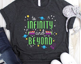 May include: A dark gray t-shirt with the text "to infinity and beyond" in green and purple. The shirt has a space theme with stars, planets, and a rocket ship.