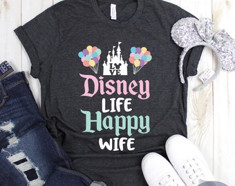 May include: A dark grey t-shirt with a pink and teal graphic design. The graphic features a castle with balloons, the text "Disney Life Happy Wife", and a Mickey Mouse head.