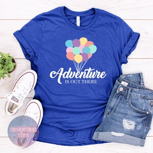 May include: A royal blue t-shirt with a white graphic of colorful balloons and the text "Adventure is out there".