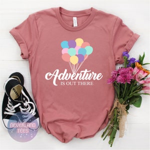 May include: A dusty rose t-shirt with a white graphic of colorful balloons and the text "Adventure is out there".