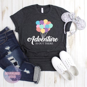 May include: A dark gray t-shirt with a white graphic of colorful balloons and the text "Adventure is out there".