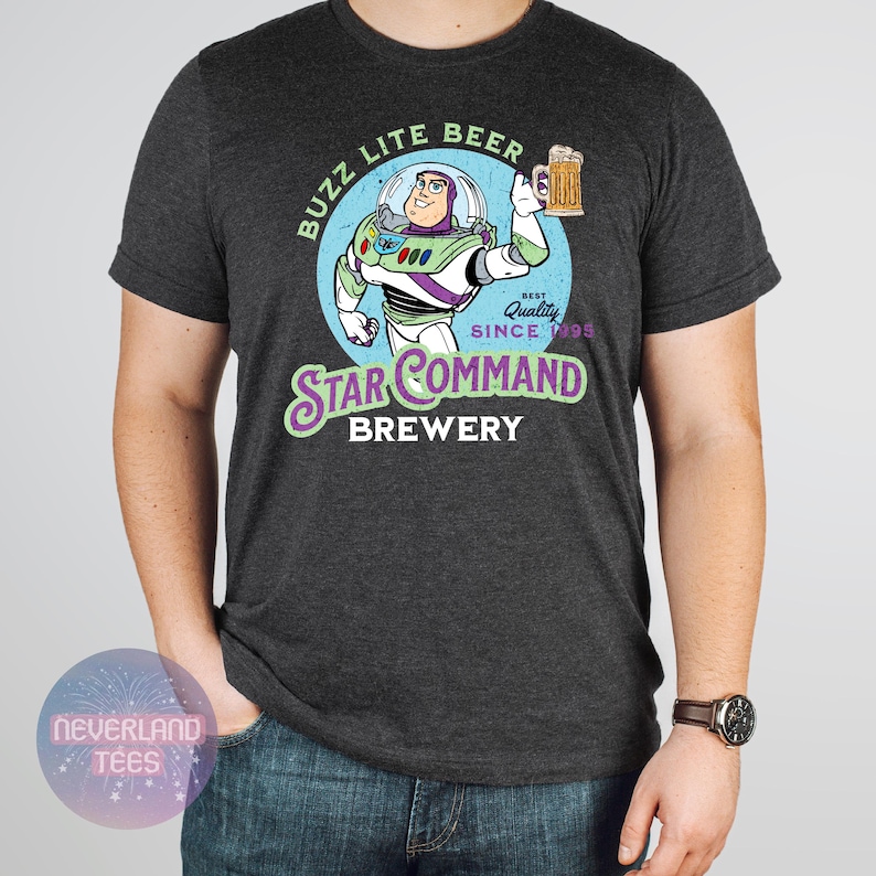 May include: Dark gray t-shirt featuring a cartoon image of Buzz Lightyear holding a beer mug, with the text "Buzz Lite Beer" and "Star Command Brewery". The design includes the words "Best Quality Since 1995".